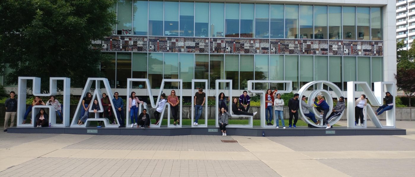 CityLAB students pose outside of Hamilton City Hall on the interactive Hamilton initial sign