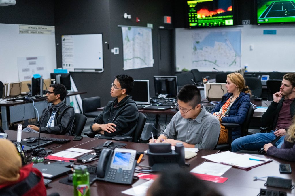 Students sit in a computer lab, listening to a lecture.